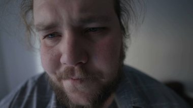 Person having heart problems suffering heart pulpitations. One young overweight man with worried emotion sitting down on couch having chest pressure