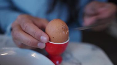 Oeuf a la coque. Hand breaking top soft egg head. Morning breakfast nutritious food rich in protein