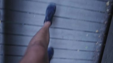 Man point of view walking outdoor at wooden bridge. Person POV shoes and feet