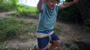 One small boy jumping outside during trail. Active child jumps in the air. Childhood development exercise outdoors in nature