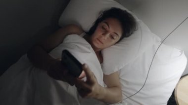 Cep telefonunu kapatan bir kadın gece yatağında uzanıyor. Akıllı telefon ekranına bakan kadın aygıtı kapatıp ışığı kapatıyor ve uykuya dalıyor.