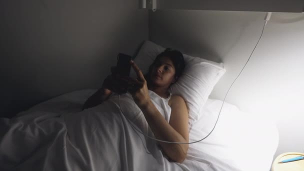 寝る前の夜にスマートフォンのデバイス画面を見てベッドに横たわっ女性 — ストック動画