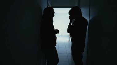 Silhouette of couple standing in corridor in crisis. Parents with child feeling worry and anxiety. Husband and wife discussing difficult situation