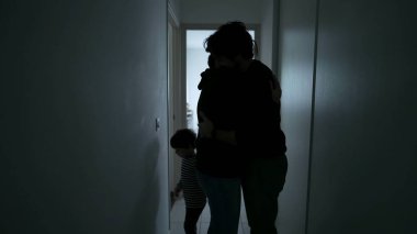 Wife suffering from mental illness standing in dark hallway. Husband embracing woman showing love and support during depression. People caring for each other