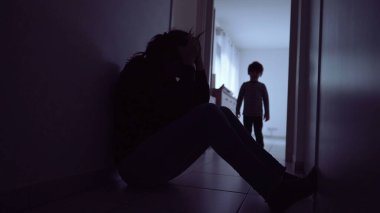 Child hugging mother suffering at home floor. Little boy silhouette consoling parent during depression. Single mother with kid