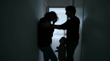 Wife suffering from mental illness standing in dark hallway. Husband embracing woman showing love and support during depression. People caring for each other