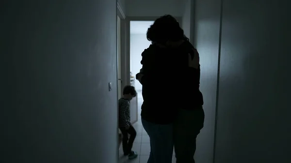 Wife suffering from mental illness standing in dark hallway. Husband embracing woman showing love and support during depression. People caring for each other