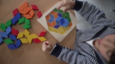 Child playing with colorful puzzle on table. Top view perspective of little boy plays with creative toy