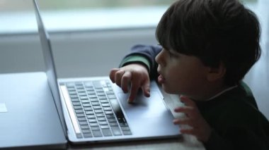Evde dizüstü bilgisayar kullanan küçük bir çocuk. Modern teknoloji cihazının önündeki çocuk