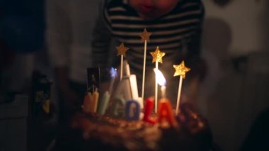 Child blowing birthday cake candles celebrating anniversary. 4 years old celebration with the name Nicolas