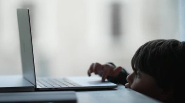 Küçük çocuk evde bilgisayar kullanarak modern teknoloji cihazını kullanmayı öğreniyor. Ekranın önündeki küçük çocuğun samimi yaşam tarzı
