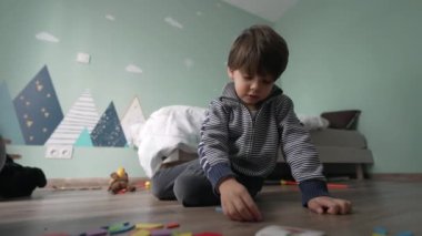 Yatak odasında oynayan küçük bir çocuk. Yerde oturan çocuk oyuncaklarla oynuyor
