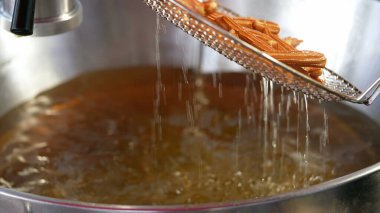 Kızarmış churro hazırlıyorum. Sokak yemekleri satıcısı büyük yağlı tavada churros hazırlıyor. Churro İspanyol geleneksel yemekleri