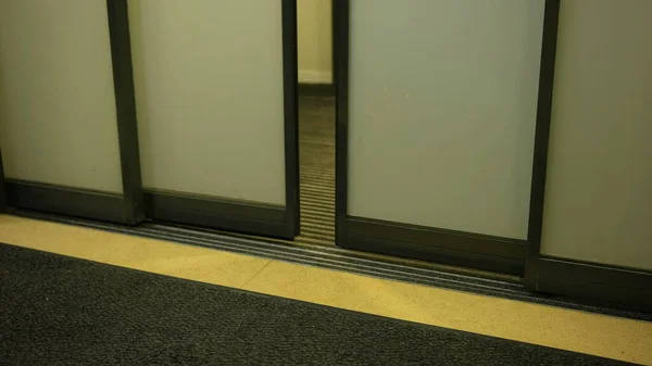 Contactless Automatic Doors Close. Frosted glass door shutting. Closeup floor carpet. Exit and enter building