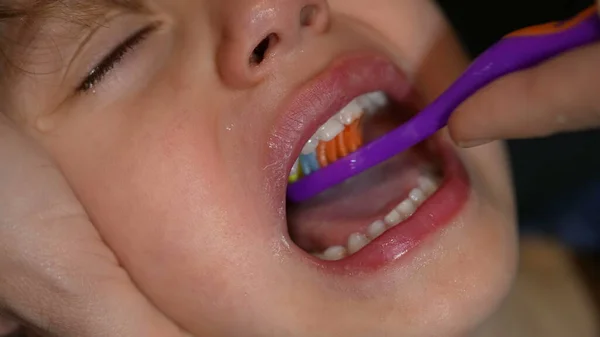 Parent brushing child mouth macro closeup. Taking care of dental hygiene. Bedtime night routine