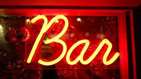 Bar neon sign in bright red color display. Entertainment signal illuminated glowing at night