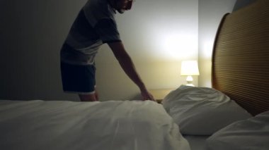 Person going to bed and sleep. Man lays down and turns off light besides bedside