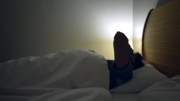 男はベッドサイドランプをオンにし ベッドから出る 日の出時刻の早い日から始まる者 — ストック動画