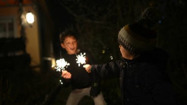 Happy children holding sparkler during holidays. Kids celebrating event festivities at night