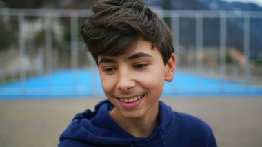 Parkta gülümseyen mutlu bir genç çocuk. Yakışıklı bir gencin portresi.