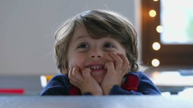 One handsome 2 year old child posing for camera. Closeup face of a cute handsome young boy with hand in chin