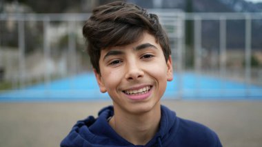 Portrait of a happy young boy smiling at camera. Closeup teenager male kid stands outdoors laughing