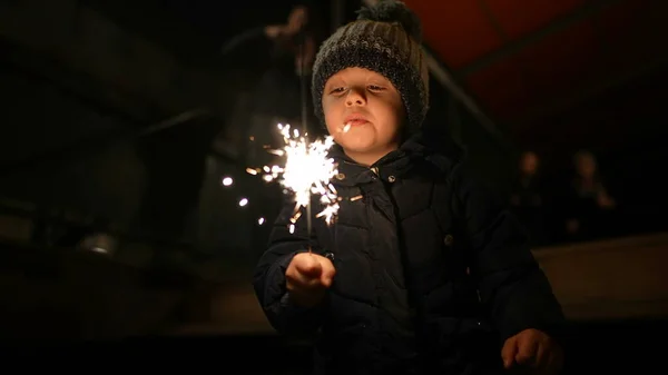 Happy small boy holding fire sparkler celebrating new year festivities in slow motion