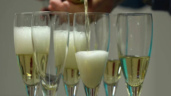 倒香槟 把香槟倒进许多杯子里 调酒师把香槟倒入玻璃杯特写 酒杯中的气泡和泡沫上升 — 图库照片