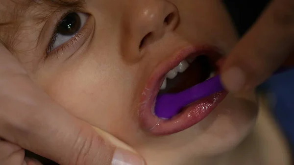 Parent brushing child mouth macro closeup. Taking care of dental hygiene. Bedtime night routine