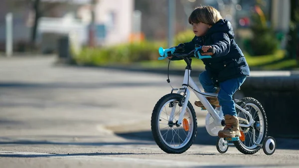 市内公園の外で冬のシーズン中に子供用自転車に乗る 自転車に乗ることを学ぶ子供サイクリスト — ストック写真