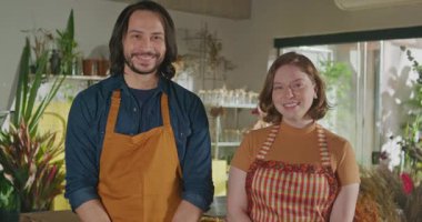 Happy male and female employees wearing staff inside small business store portrait faces close up