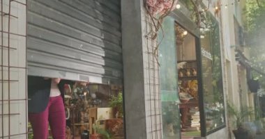Front of shop store. Woman sliding business entrance. Independent female small business owner in middle age opening commercial store.