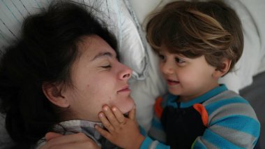 Çocuk annesini yatakta uyandırıyor. Otantik gerçek hayatta küçük çocuk sabah ebeveynini uyandırır.