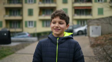 One handsome young boy walking outdoors in city park during winter season