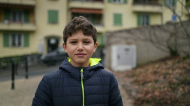One handsome young boy walking outdoors in city park during winter season