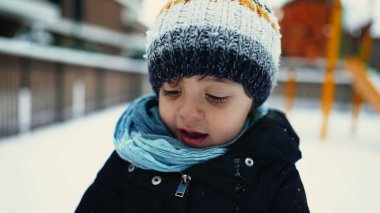 Kışın dışarıda duran bereli eşarp ve palto giyen genç bir çocuk. Aralık 'ta çocuğun portresi