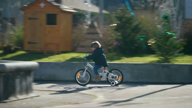 Dışarıda bisiklete binen küçük aktif bir çocuk. Şehir parkında bisiklet süren sportif bir çocuk.