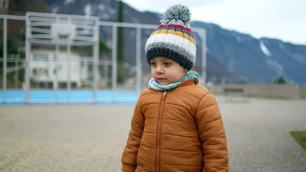 stock image Small child standing at city park wearing winter clothes. One little kid with beanie scarf and jacket