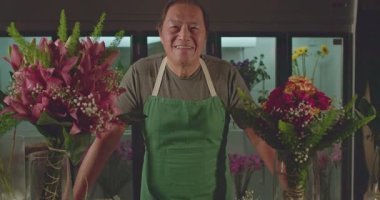 Portrait of a Japanese florist smiling at camera behind workshop place. One male asian employee with happy expression. Job occupation concept