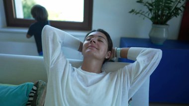 Sakin bir kadın oturma odasında kanepede dinleniyor. Huzurlu anne ellerini başının arkasına koyuyor gözlerini kapıyor ve evde mola veriyor. Stressiz konsept