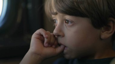 Ağzında başparmağı olan düşünceli bir çocuk trenle seyahat ederken düşünüyor. Düşüncelere dalmış küçük çocuğu kapat.
