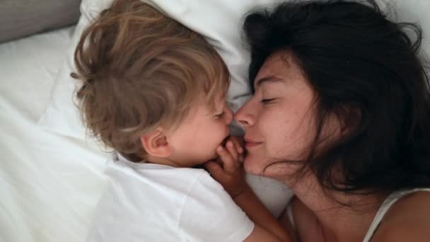 母亲和孩子的爱和照料躺在床上 妈妈和儿子周末接吻的生活方式时刻 — 图库视频影像