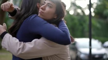 Two friends hugging each other standing outside with EMPATHY and SUPPORT. Friendship concept of female friend EMBRACING suffering person