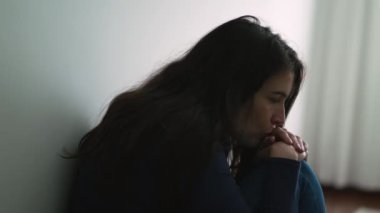 Düşünceli depresif kadın evde oturmuş duvara yaslanıyor ve duygusal sorunları düşünüyor.