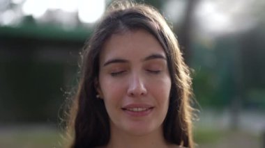 Meditasyonda gözlerini kapayan barışçıl bir kadın. 30 'lu yaşlarda düşünceli bir insan doğanın dışında kapalı gözlerle bakar.