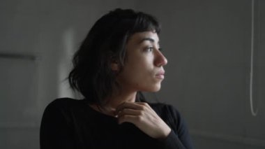 Pencere kenarında durup düşünen düşünceli bir İspanyol genç kadın. Düşünceli bir Güney Amerikalı kız.