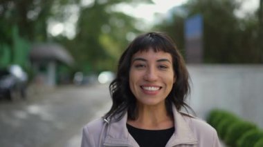 Gülümseyerek kameraya doğru yürüyen mutlu bir İspanyol kadının portresi. Neşeli Brezilyalı kişi