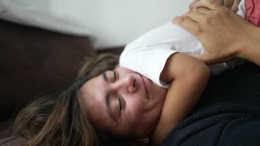 Annesini kucaklayan çocuk kanepede uzanıyor. Küçük çocuk annesinin kucağına yattı. Ebeveyn ve çocuk şefkat kavramı