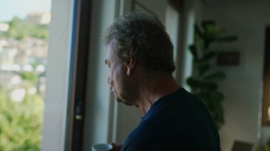 Emekli bir son sınıf öğrencisi evde kahve ya da çay içiyor. Düşünceli, olgun bir erkek sabahın köründe elinde kupayla manzaraya bakıyor.