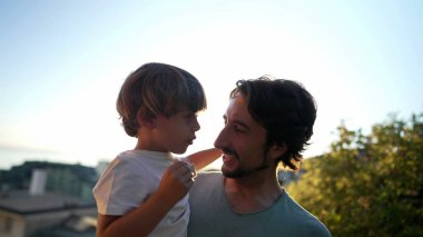 Gün batımında babayı kucaklayan çocuk. Altın Saat 'te baba oğul kaynaşma anı. Ebeveyn ve küçük çocuk kucaklaşması. Babalık kavramı